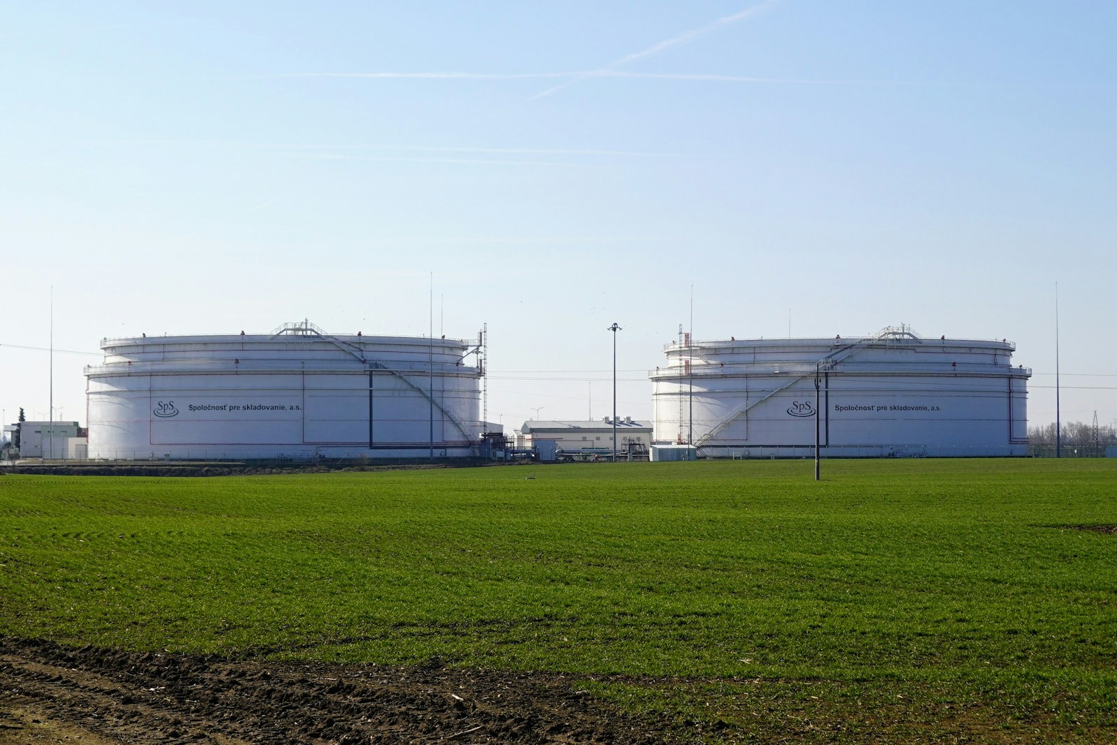 Two large white storage tanks in a field